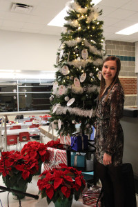 8th grader, Lizzie Dagg, poses in a stylish, long-sleeved dress in front of the Angel Tree for Student Council's annual Angel Tree Dinner.