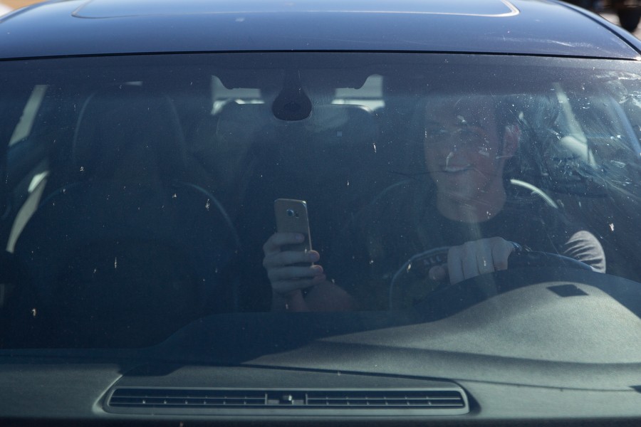 Hudson McCabe uses his phone while driving through the school parking lot on Tuesday, Feb. 9 at Argyle High School inArgyle, TX. (Caleb Miles / The Talon News)