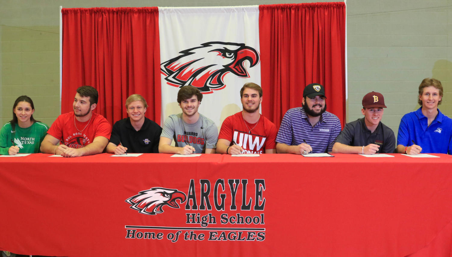 From left to right, seniors Hannah Gladys, Owen Petrie, Cale Nanny, Wes McCollum, Jon Copeland, Preston Coyle, Ben Pound, and Will Gilster commit to their colleges on National Signing Day at AHS in Argyle, Texas on Feb. 7, 2018. (Campbell Wilmot / The Talon News)