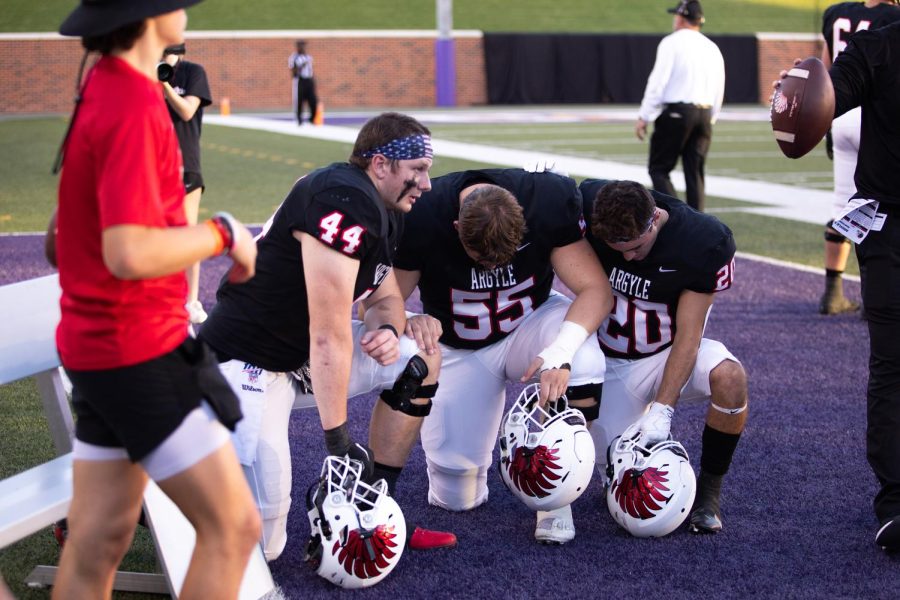 Seniors Riley Van Poppel, Jason Crowder, and Dax Horany engage in prayer before competing against the Montgomery Bears at the University of Mary Hardin-Baylor Crusader stadium on September 12, 2022.
